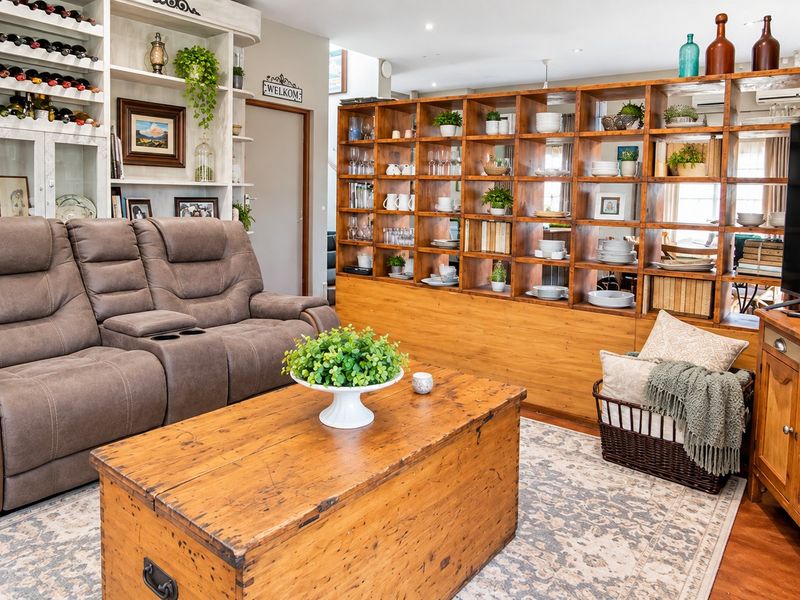 A cozy living room featuring extensive built-in shelving, recessed lighting, and warm-toned laminate flooring, creating a functional and inviting space.