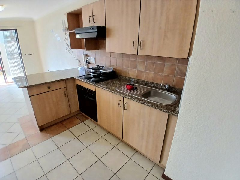 A functional kitchen featuring laminate cabinetry, granite countertops, built-in oven, hob, and extractor fan, with tiled flooring and backsplash.