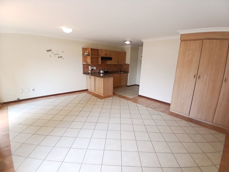 Open-plan living area featuring tiled flooring, built-in kitchen cabinetry with laminate countertops, and a large built-in storage cupboard.