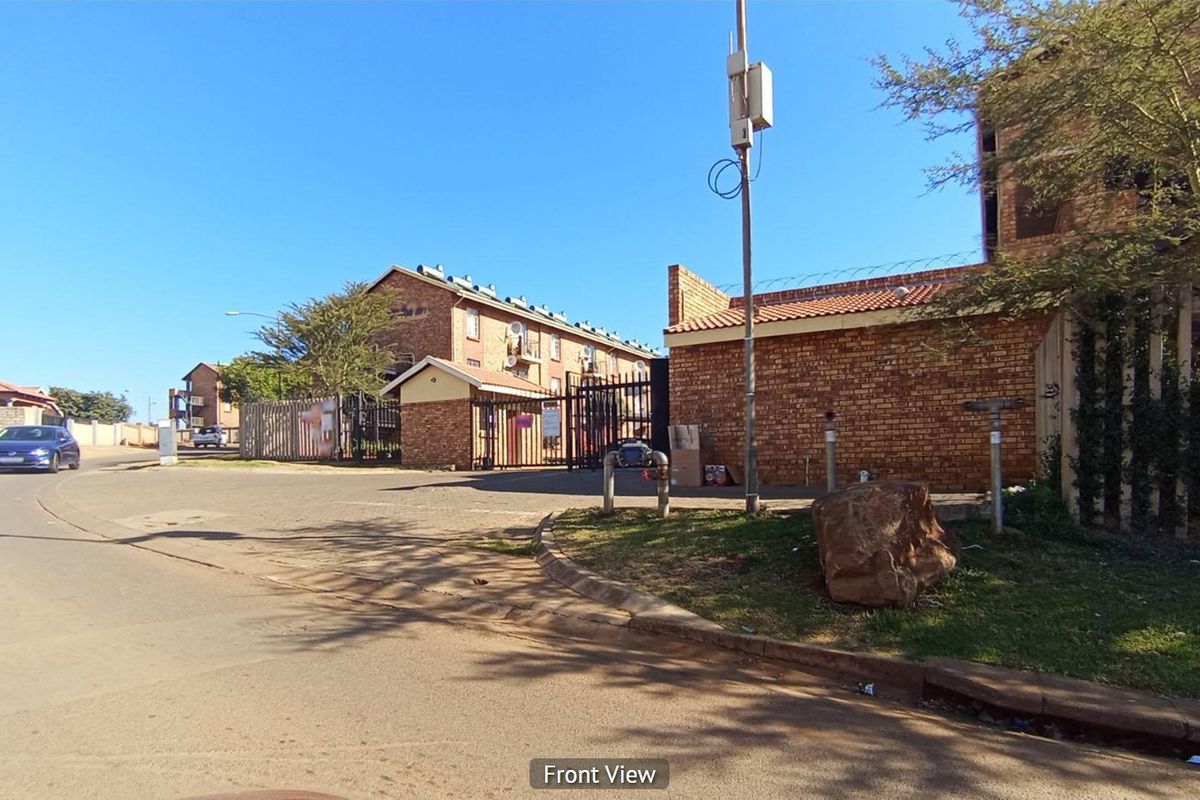 Street view showing the entrance and exterior brick boundary wall of the apartment complex.