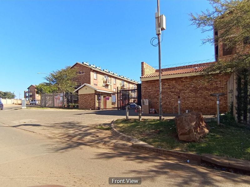 Street view showing the entrance and exterior brick boundary wall of the apartment complex.
