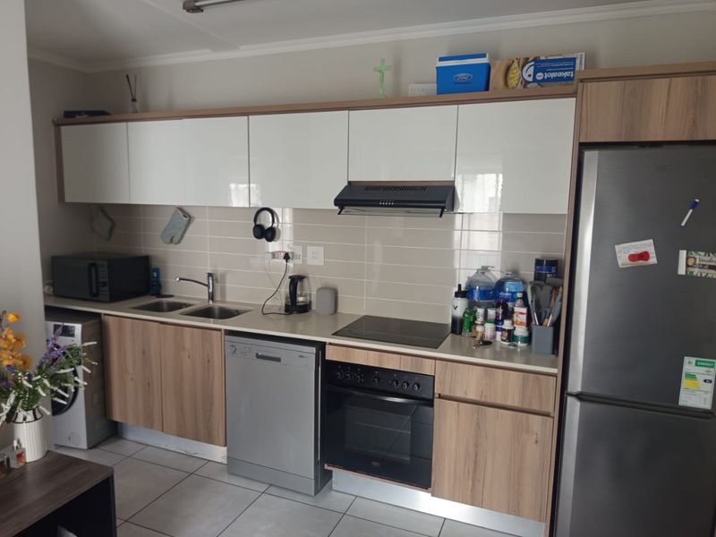 Modern kitchen featuring wood-look and white cabinetry, integrated appliances, double sink, and tiled backsplash with neutral floor tiles.