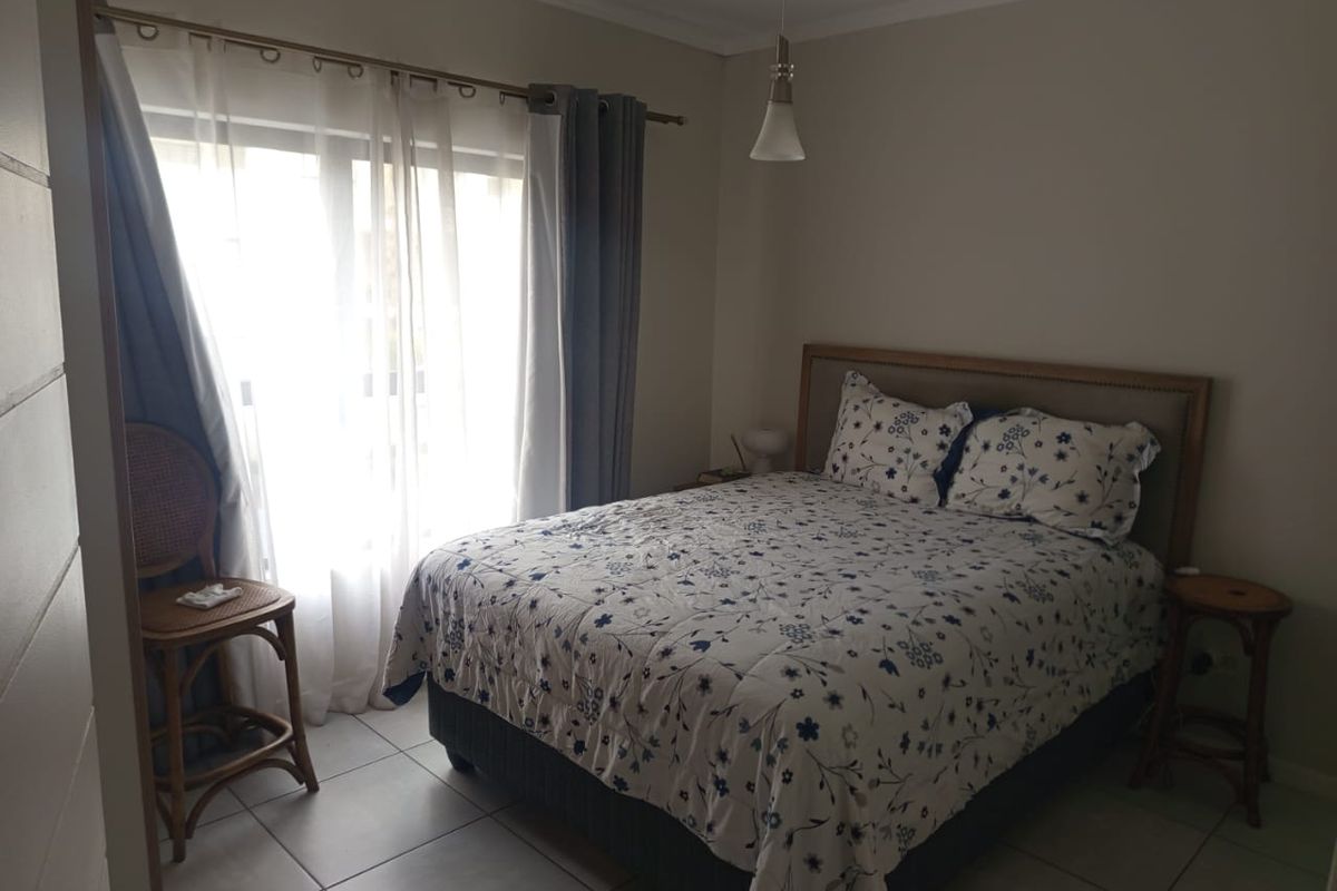 A bedroom featuring tiled flooring, a pendant light fixture, and a sliding glass door providing access to an outdoor area.