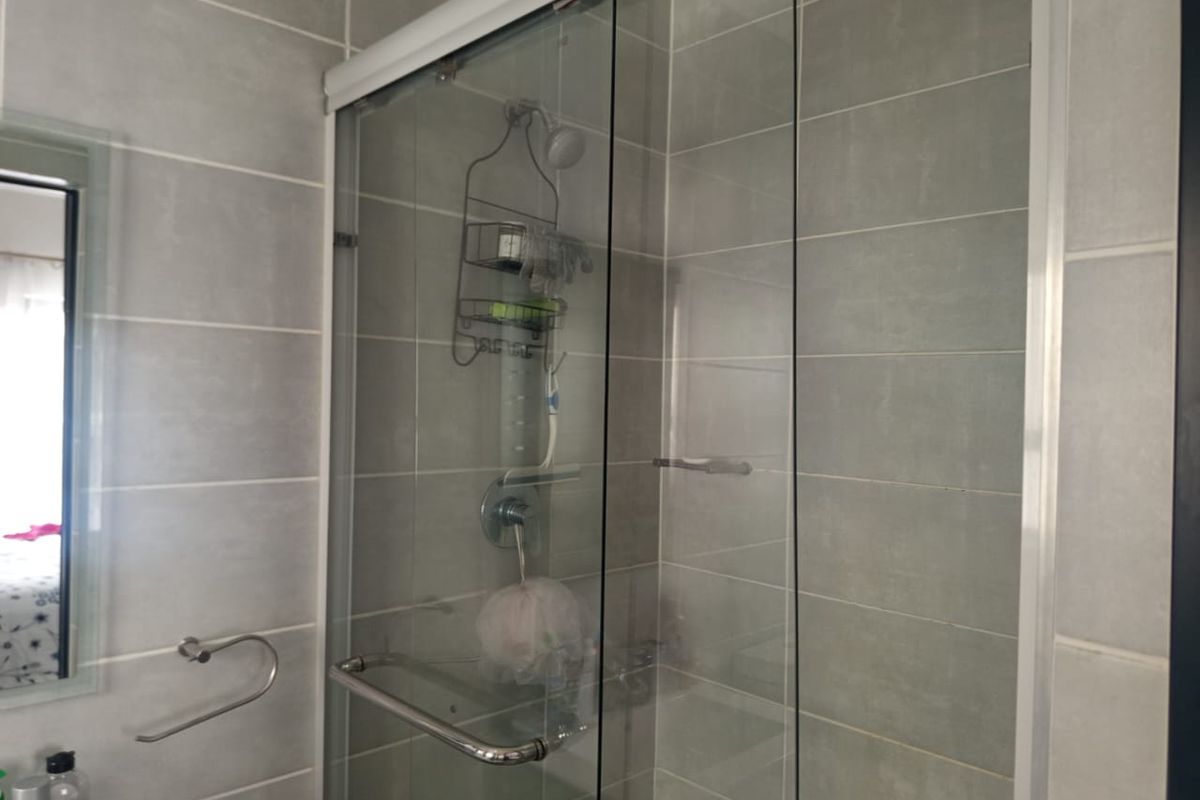 A modern bathroom featuring a glass-enclosed shower with grey wall tiling and chrome fixtures.