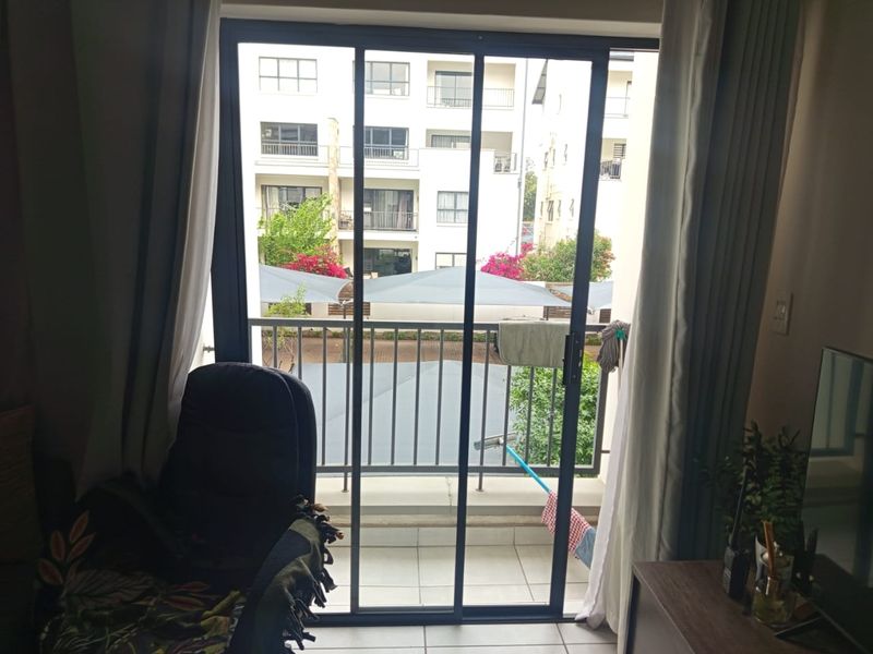 A view from the interior looking out through a sliding glass door onto a private balcony with metal railings.