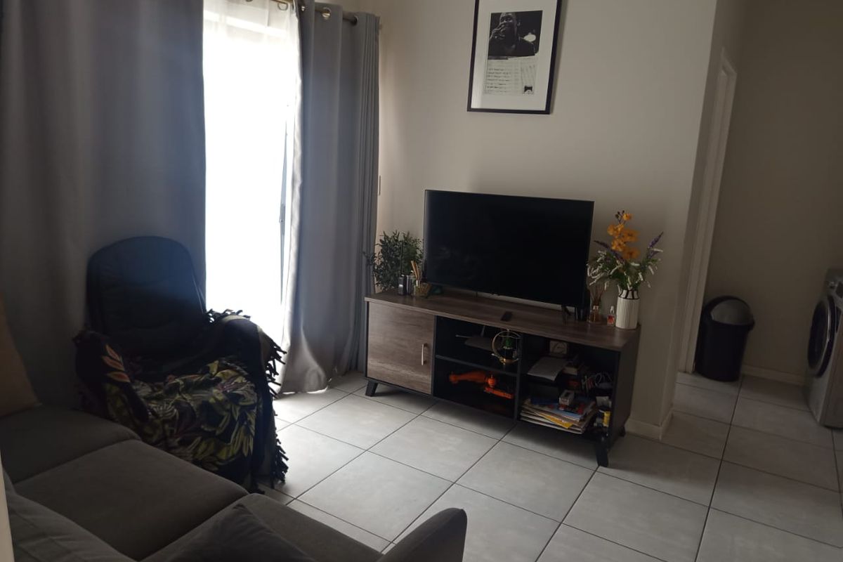 A living room area featuring neutral tiled flooring and a sliding glass door providing natural light access.