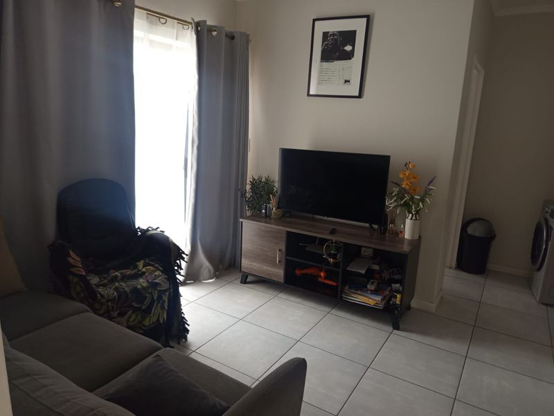 A living room area featuring neutral tiled flooring and a sliding glass door providing natural light access.