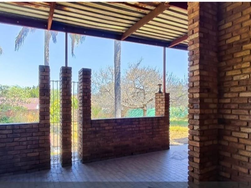 Covered outdoor patio featuring exposed brick walls, brick pillars, and a built-in counter, offering a rustic space for outdoor entertaining.