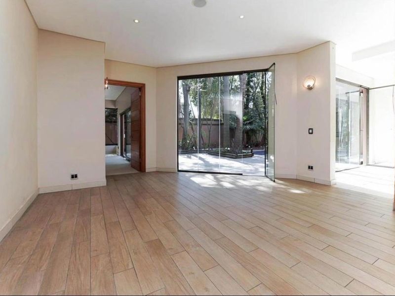 Spacious, light-filled living area featuring wood-look tile flooring, a stone-clad feature pillar, and seamless access to the garden through frameless glass stacking doors.