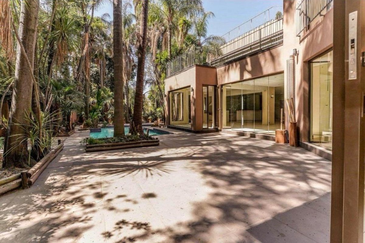 Rear exterior view featuring a paved patio area, swimming pool, and large glass sliding doors leading into the home.