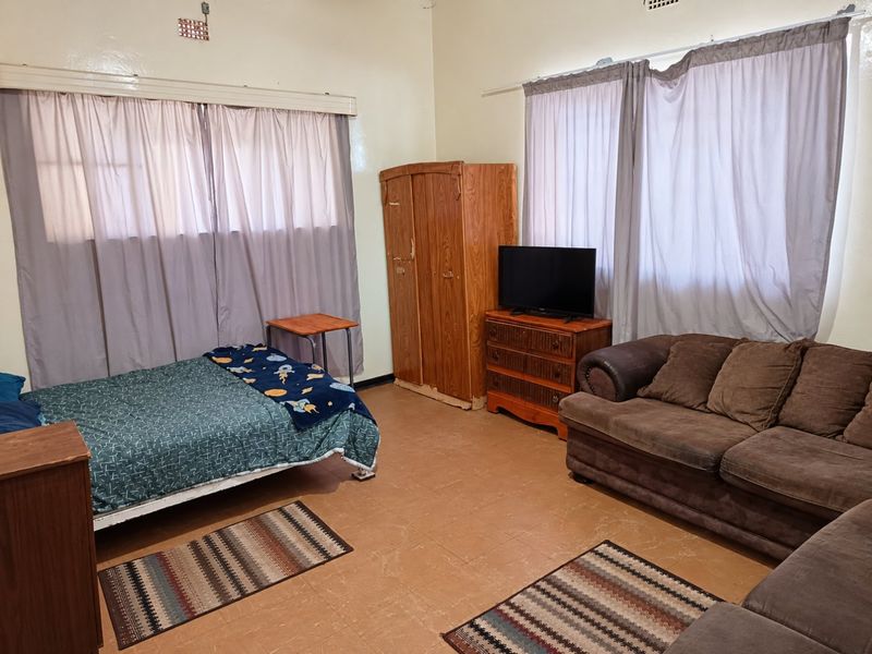 A spacious bedroom featuring tiled flooring and dual windows with curtain rails, offering a functional layout ready for cosmetic updates.