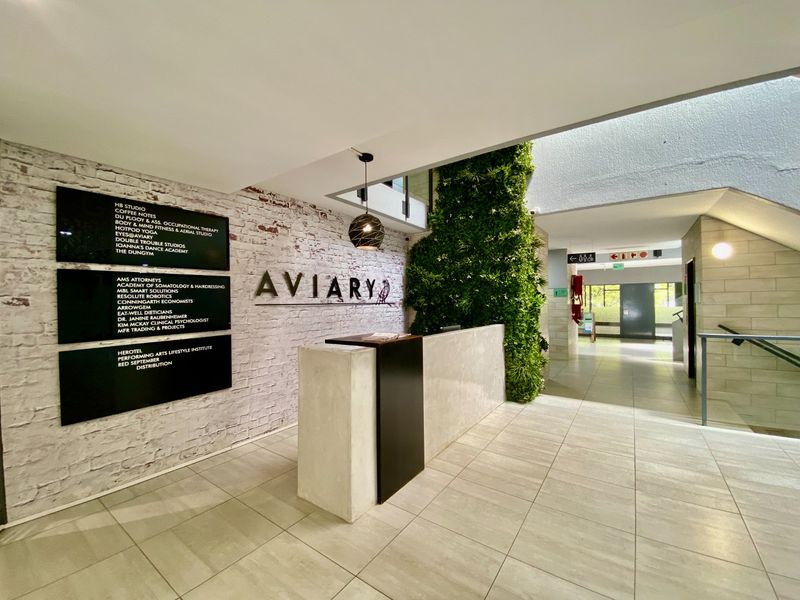 Modern commercial building entrance featuring a reception desk, directory signage, exposed brick wall, and a vibrant vertical garden feature.