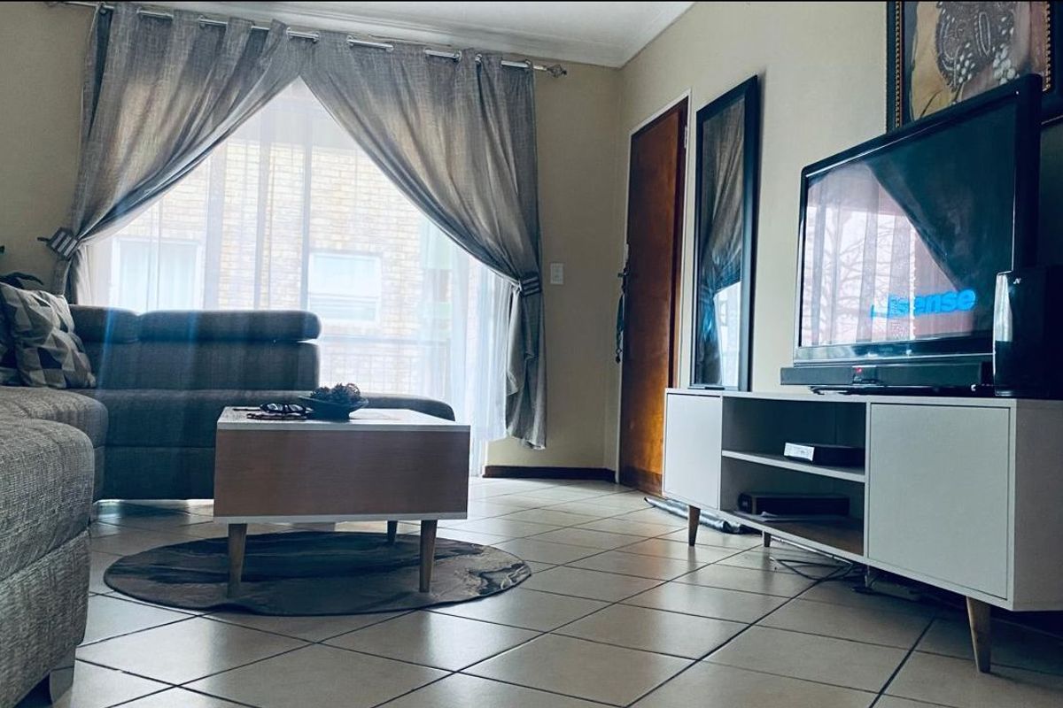 A comfortable living room featuring tiled flooring and a sliding glass door that provides natural light.