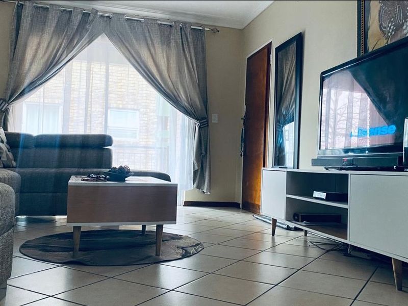 A comfortable living room featuring tiled flooring and a sliding glass door that provides natural light.