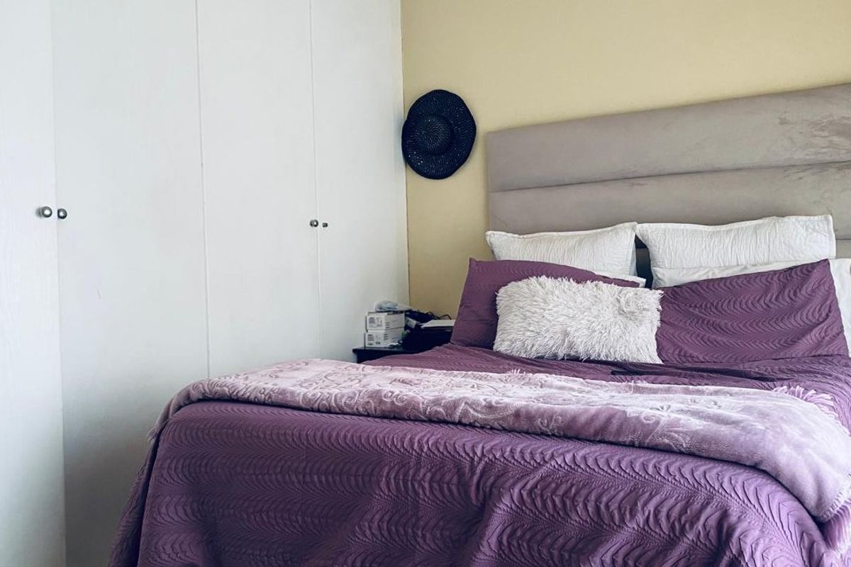 A bedroom featuring built-in cupboards and a neutral wall finish, providing a functional space for rest.