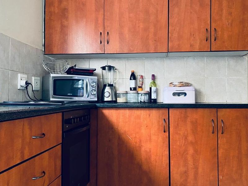 A functional kitchen featuring wood-look laminate cabinetry, tiled backsplash, and a built-in oven with dark laminate countertops.