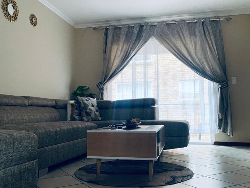 A comfortable living room featuring tiled flooring and a sliding glass door that provides natural light.