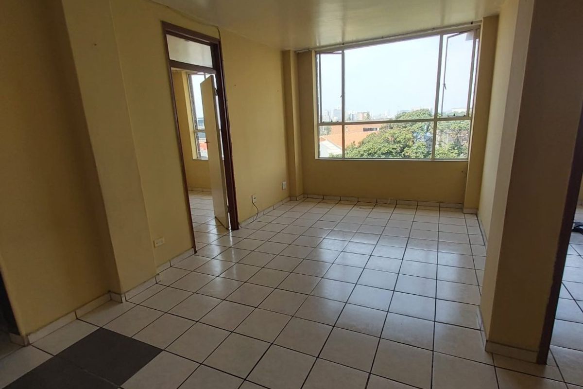 An empty living room featuring tiled flooring, large windows with natural light, and neutral wall finishes, ready for personalization.