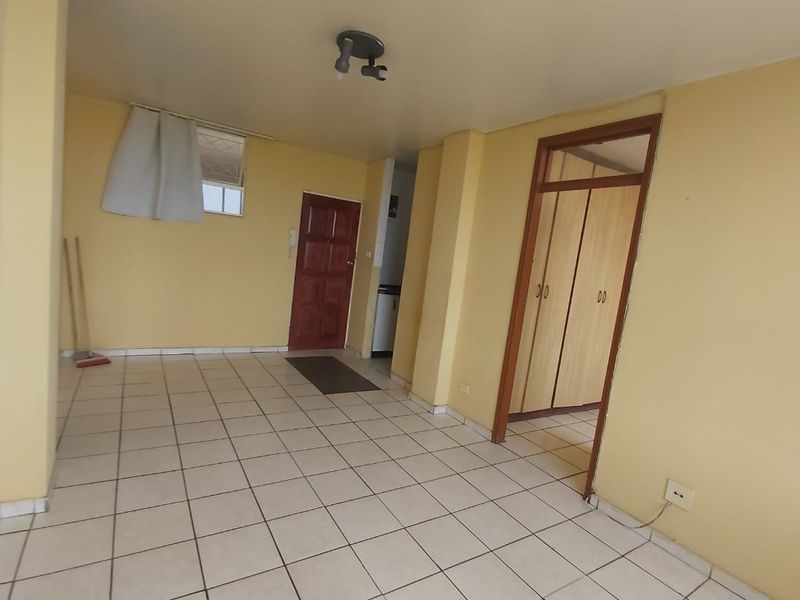 An empty living area featuring tiled flooring, built-in storage cupboards, and neutral wall finishes, offering a blank canvas for potential interior updates.