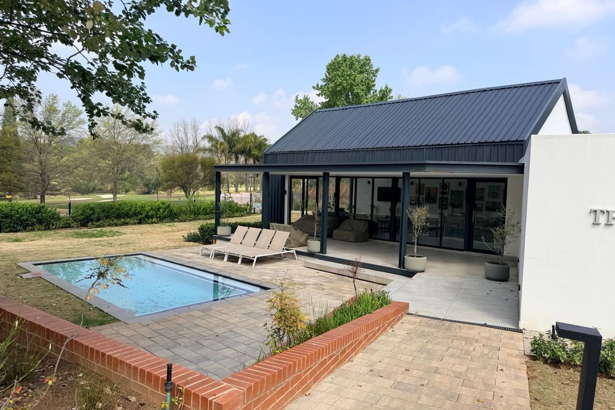 A modern rear exterior view featuring a covered patio, a swimming pool, and a paved terrace area set against a landscaped garden.