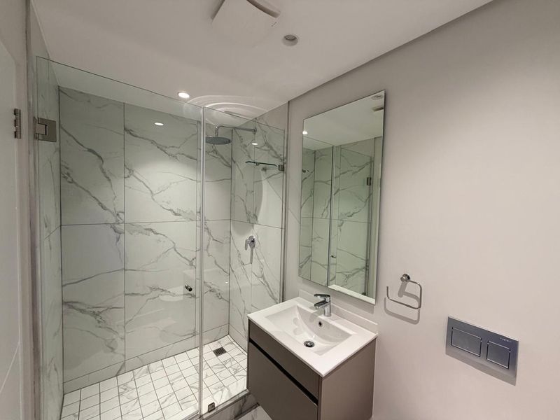 Modern bathroom featuring a walk-in shower with marble-look tiling, a wall-mounted vanity with basin, and a concealed cistern flush plate.