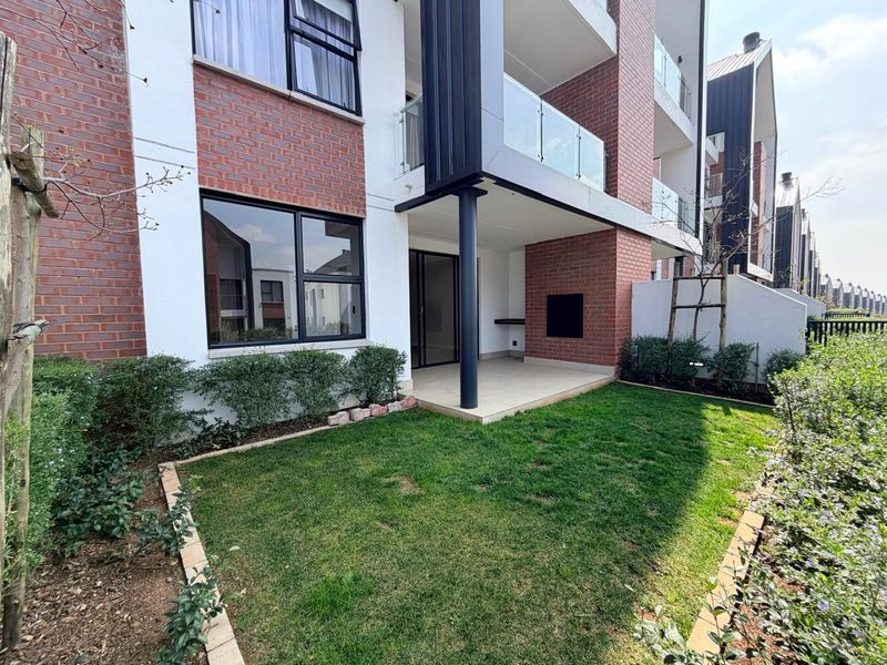 A modern apartment exterior featuring a private garden, covered patio with a built-in braai, and contemporary brick and glass architectural finishes.
