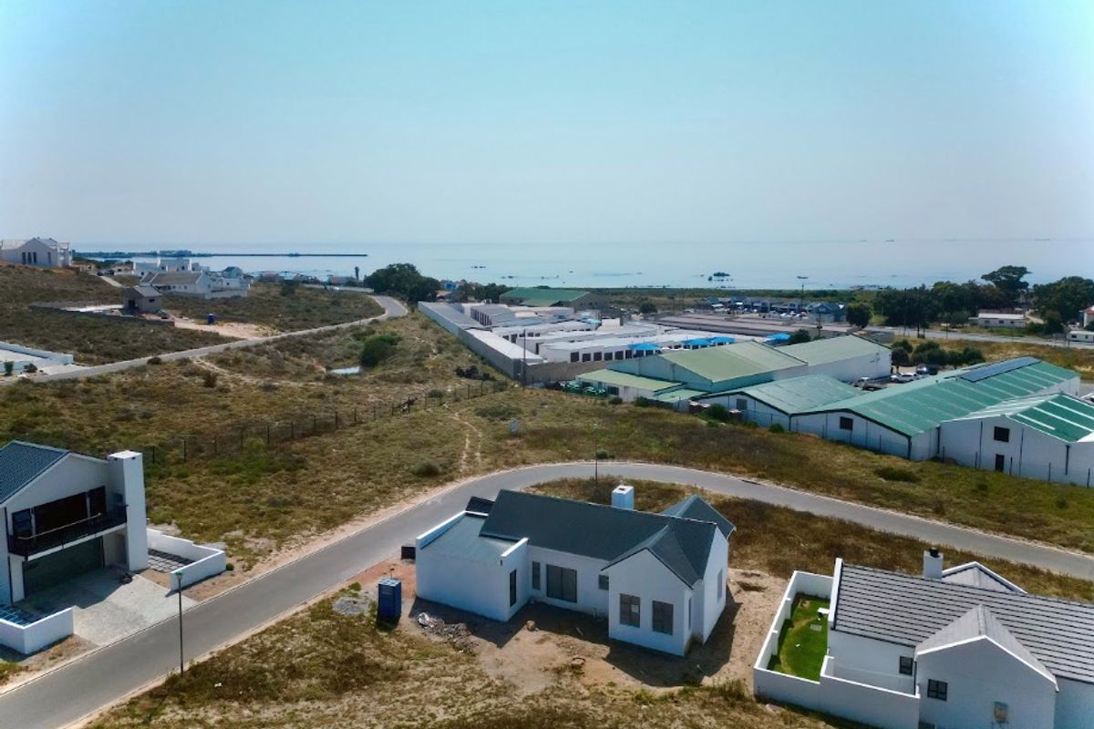 Aerial view of a coastal residential development featuring modern homes with pitched roofs and proximity to the ocean.