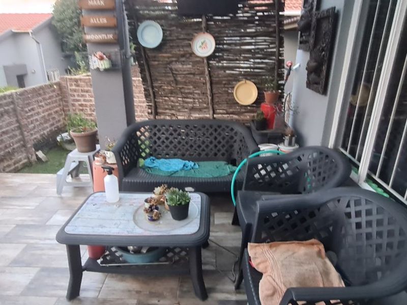 A covered patio area featuring tiled flooring and direct access to the apartment through a sliding door with a security gate.
