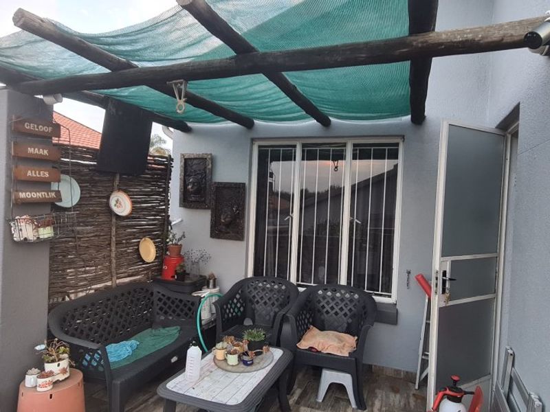 A covered patio area featuring a timber pergola with shade cloth, security gate, and security bars on the window.