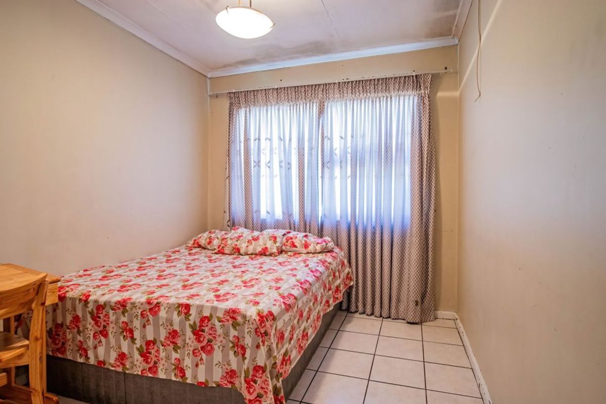A bedroom featuring tiled flooring and a ceiling-mounted light fixture, showing signs of wear on the ceiling surface.