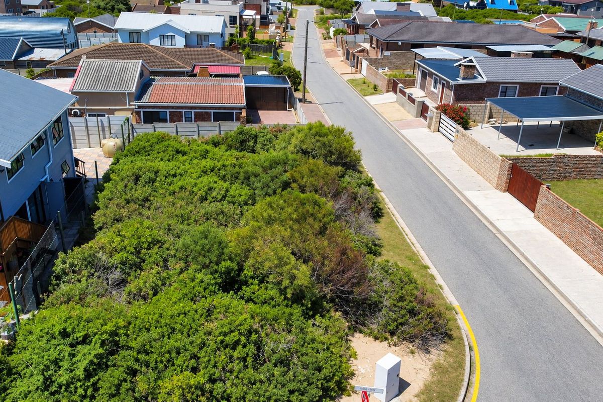 Aerial view of a vacant residential plot covered in dense vegetation, situated in a developed suburban street.