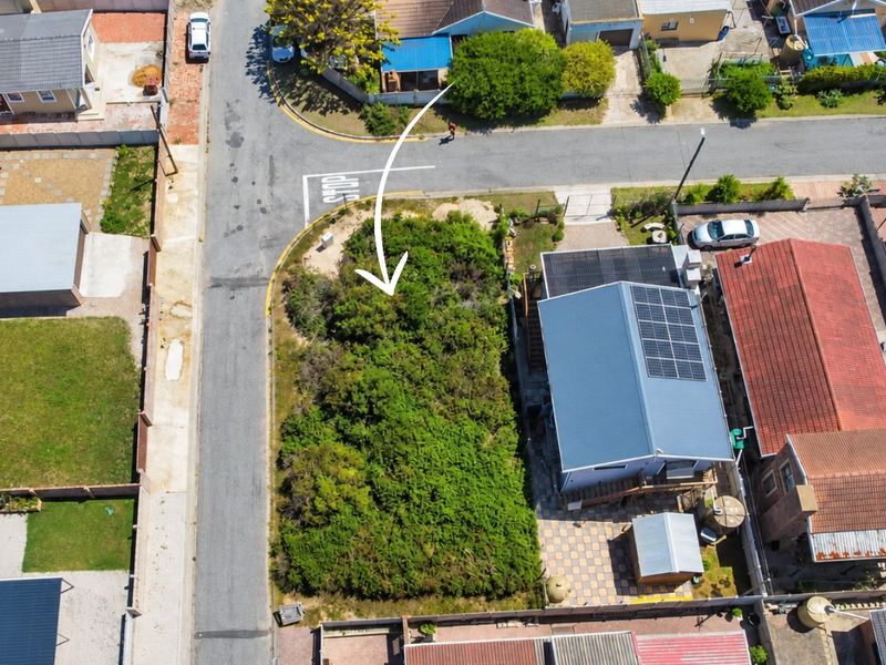 An aerial view of a vacant residential corner plot situated in a developed suburban neighborhood, ready for potential development.