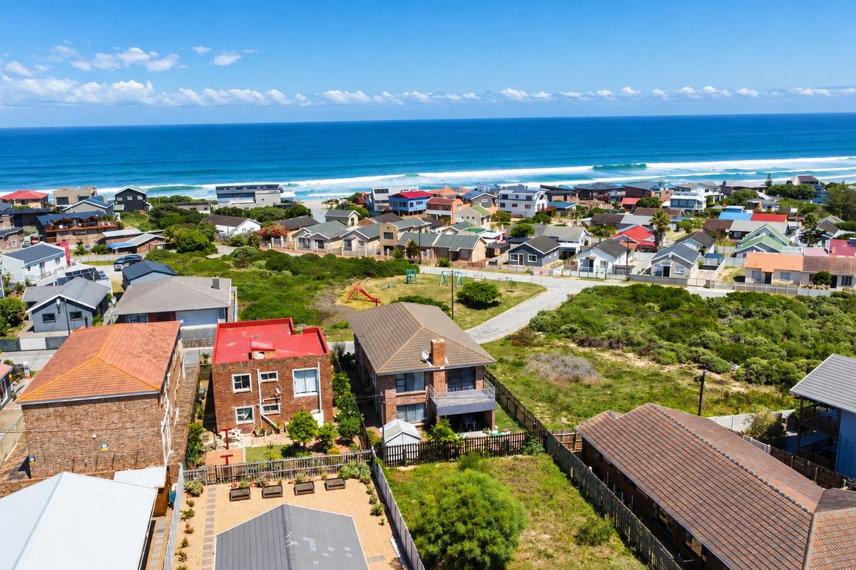 An aerial view of a coastal residential neighborhood featuring various homes, paved streets, and proximity to the ocean.