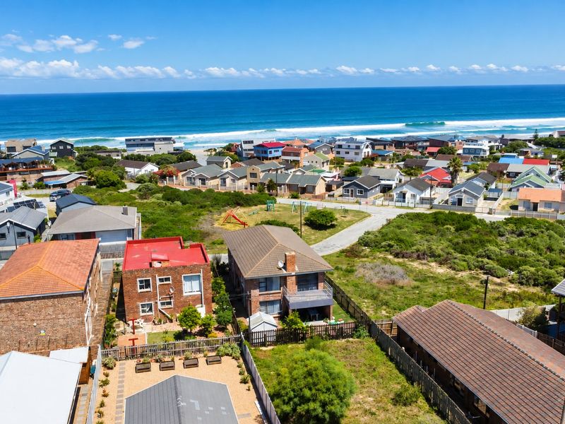 An aerial view of a coastal residential neighborhood featuring various homes, paved streets, and proximity to the ocean.