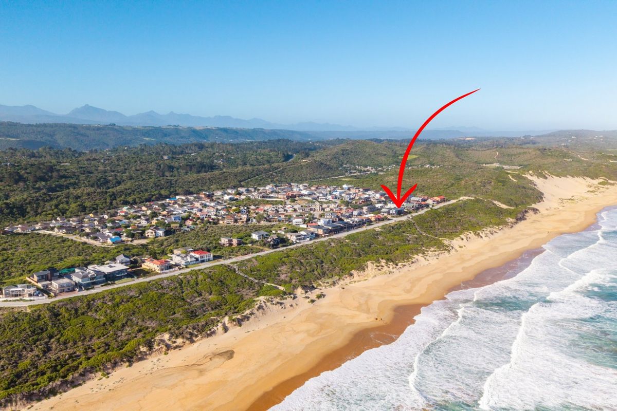 Aerial view of a coastal residential estate situated along the beachfront, showcasing the property's prime location and surrounding landscape.