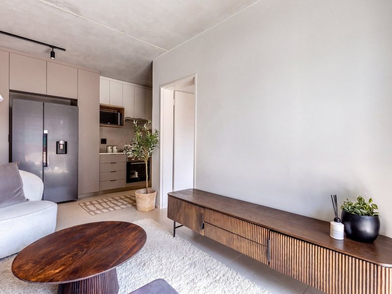 Modern open-plan living area featuring a sleek kitchen with built-in cabinetry, integrated appliances, and neutral tiled flooring throughout.