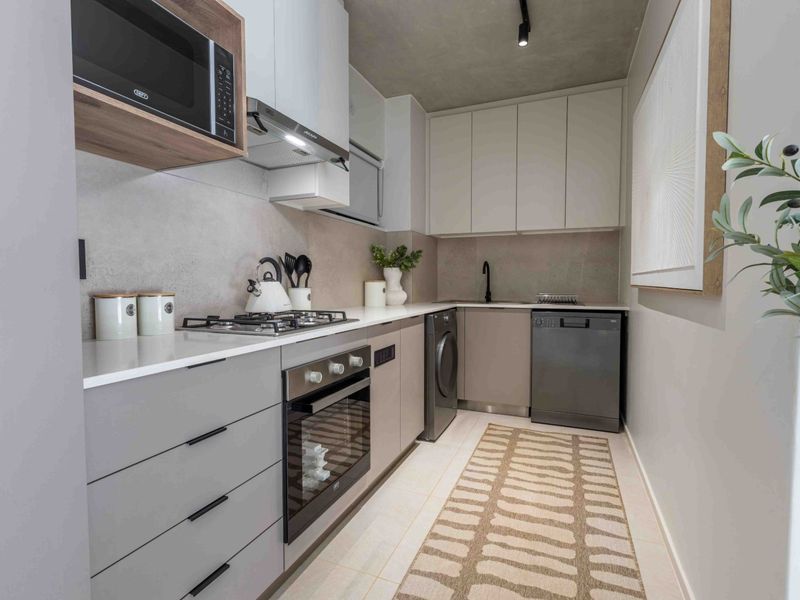 Modern galley-style kitchen featuring sleek cabinetry, stone countertops, integrated appliances, and high-quality finishes in a contemporary neutral palette.