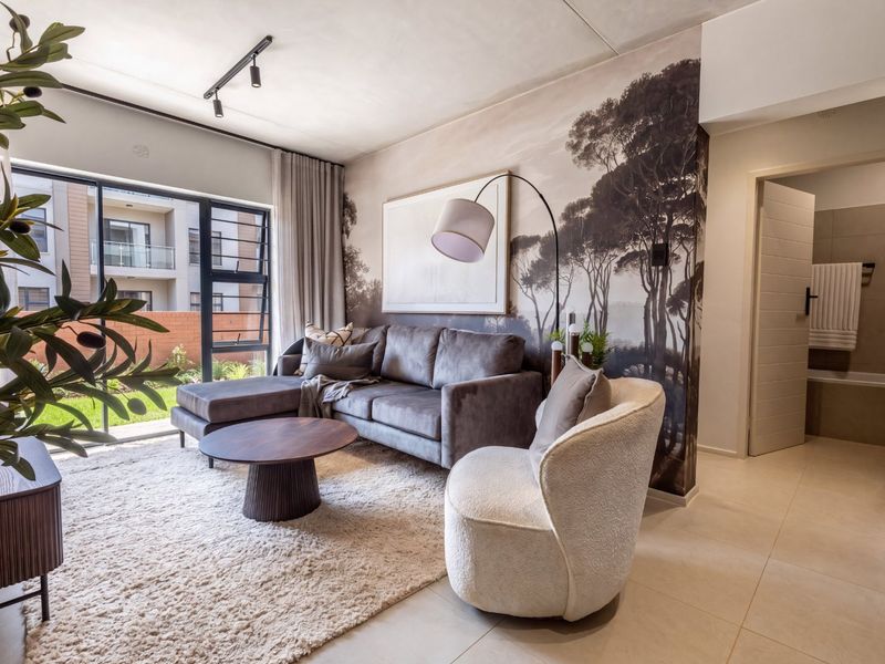 Modern living room featuring tiled flooring, track lighting, and a large sliding glass door providing natural light and access to the exterior.