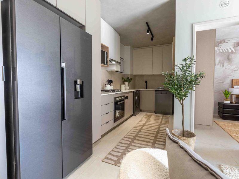 Modern galley-style kitchen featuring sleek cabinetry, integrated appliances, gas cooktop, and contemporary track lighting, seamlessly flowing into the adjacent living and bedroom areas.
