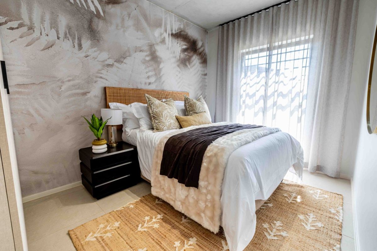 A well-presented bedroom featuring neutral tiled flooring, a decorative feature wall, and large windows with installed curtain tracks.
