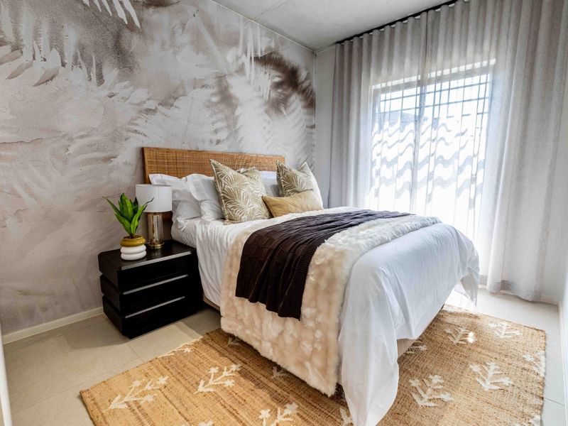 A well-presented bedroom featuring neutral tiled flooring, a decorative feature wall, and large windows with installed curtain tracks.