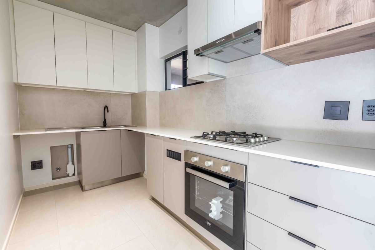 Modern kitchen featuring sleek white and grey cabinetry, stone countertops, a gas hob, built-in oven, and high-quality finishes throughout.