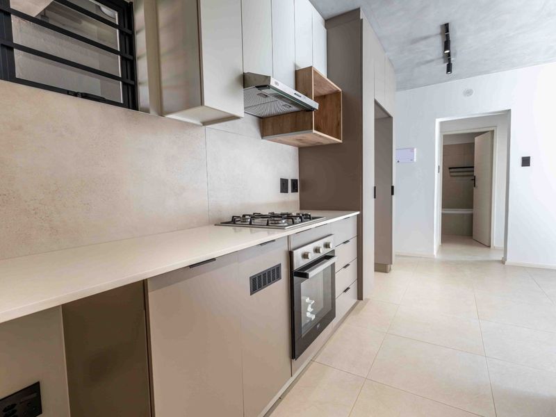Modern kitchen featuring sleek built-in cabinetry, stone countertops, a gas hob, and an integrated oven, finished with neutral floor tiles.