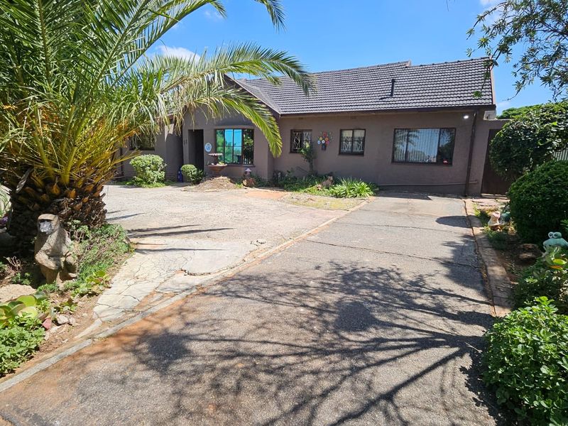Front exterior view of a single-story house featuring a tiled roof, concrete driveway, and established garden landscaping.