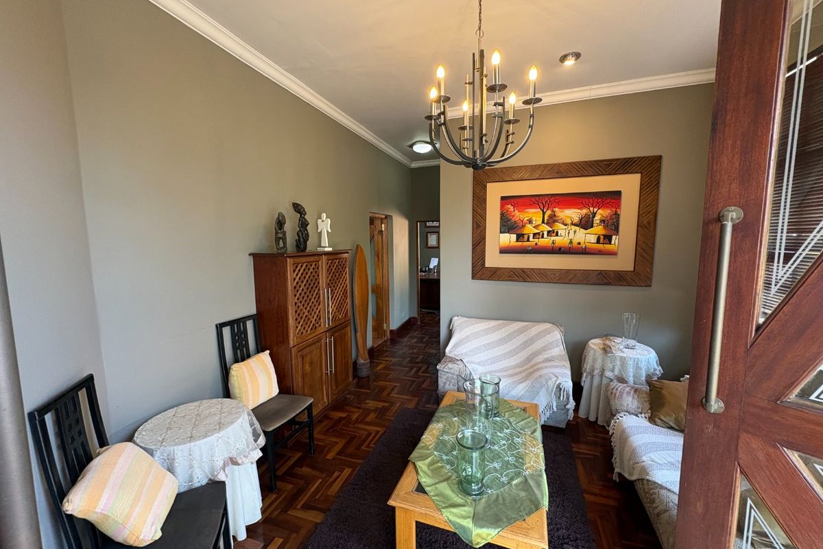 A cozy living room featuring classic parquet flooring, decorative cove cornicing, and a central chandelier, creating a warm and inviting atmosphere.