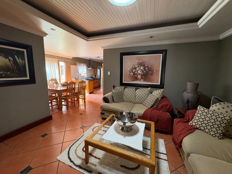 Spacious open-plan living and dining area featuring terracotta floor tiles, a coffered ceiling with recessed lighting, and a view into the adjacent kitchen.