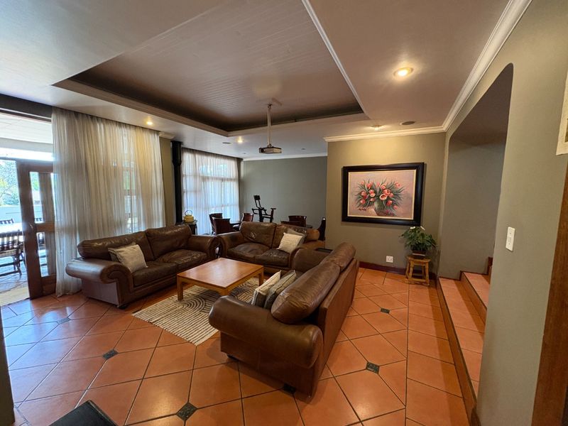 Spacious living area featuring terracotta floor tiles, a recessed ceiling with downlights, and large sliding glass doors providing access to the patio.