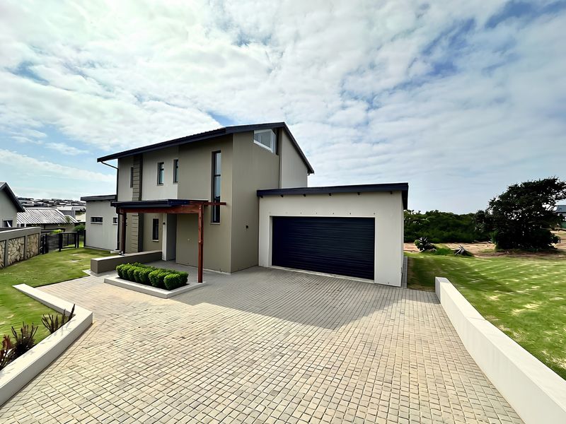Modern double-story house featuring a paved driveway, double garage, and timber pergola entrance, set within a well-maintained landscaped garden.