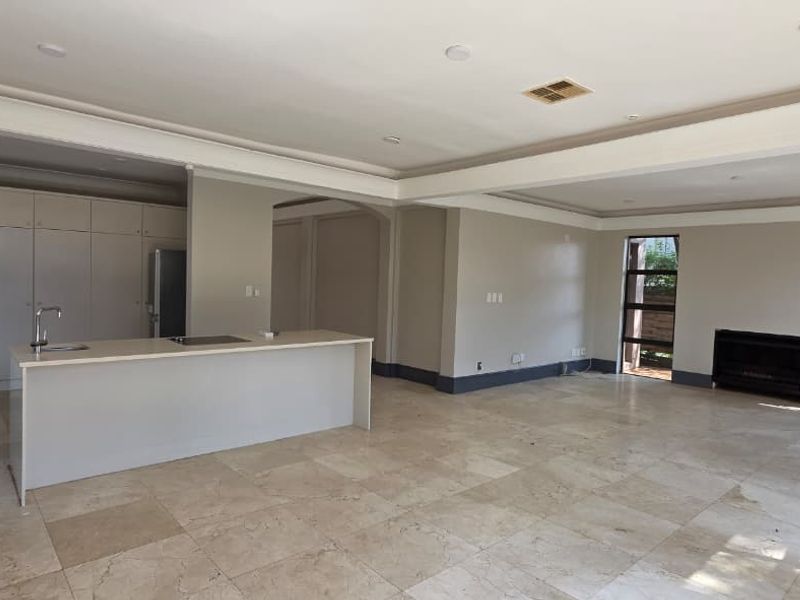 Spacious open-plan living area featuring a modern kitchen island, stone flooring, built-in fireplace, and neutral finishes throughout.