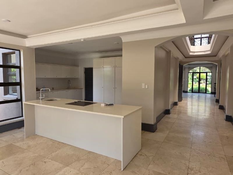 Spacious open-plan kitchen area featuring a central island, stone countertops, built-in cabinetry, and elegant tiled flooring with a bright, airy atmosphere.